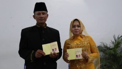 Pengantin laki-laki dan perempuan memperlihatkan buku nikah kepada para tamu undangan. Foto: Arman/M19.